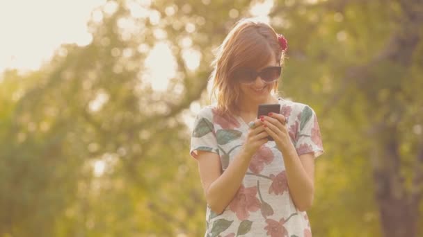 Jolie femme dans les lunettes en utilisant le téléphone portable dans le jardin 