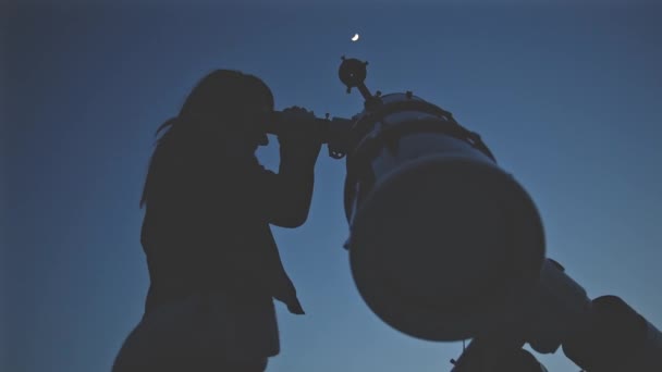 若い女性が夜に天体望遠鏡を通して見る — ストック動画