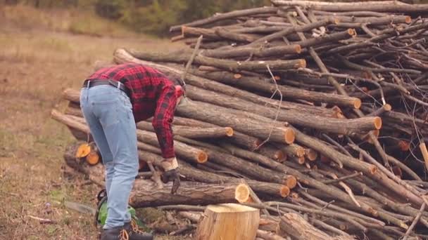 Skogshuggare Med Motorsåg Och Högen Skurna Woods — Stockvideo