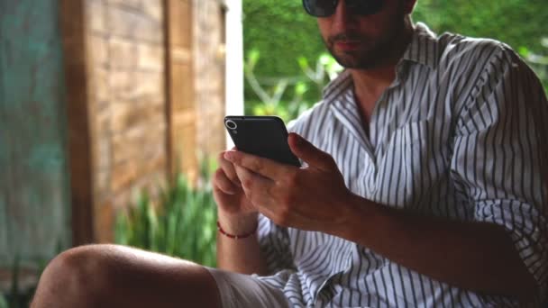 Hombre Sentado Sofá Terraza Utilizando Teléfono Inteligente — Vídeo de stock