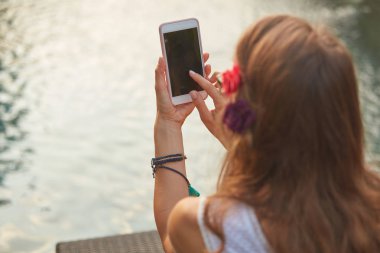 Bir yüzme havuzu güverte salonda yatarken cep telefonu kullanarak kız 