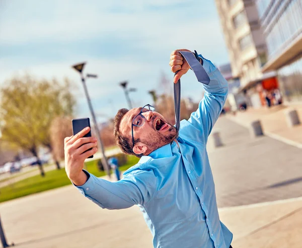 Divertido hombre de negocios enojarse mientras usa el teléfono inteligente al aire libre . —  Fotos de Stock