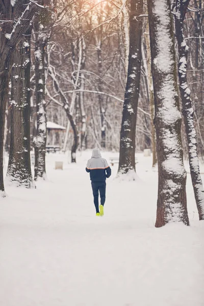 Homem correndo no parque nevado e tempo frio . — Fotografia de Stock