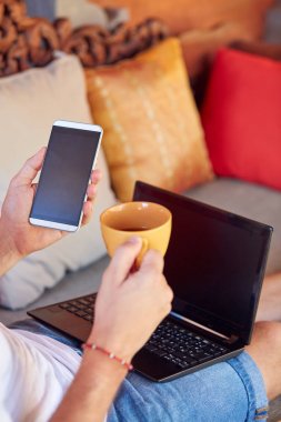 Adam cep telefonu ve laptop kullanarak TH kahve/çay içme