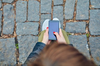 Bir tezgah üzerinde oturan ve akıllı telefon kullanarak kadın.