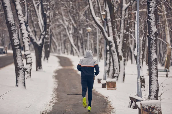 Człowiek jogging w zimnej zimie śnieżny dzień na zewnątrz. — Zdjęcie stockowe