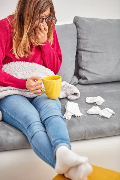 Ziek meisje Holding Cup en het drinken van koffie/thee op een bank. — Stockfoto