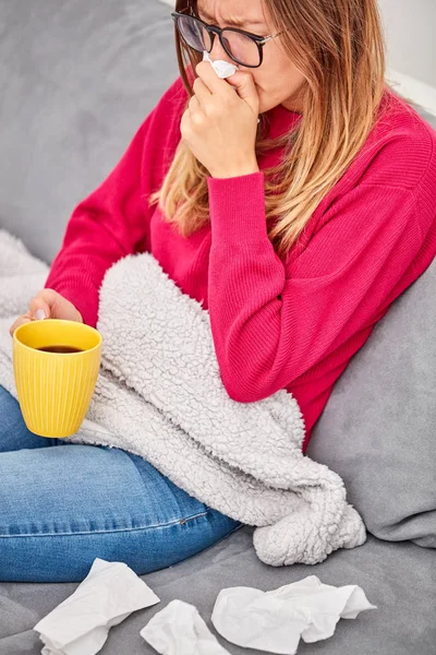 Niña enferma sosteniendo la taza y bebiendo café / té en un sofá . — Foto de Stock