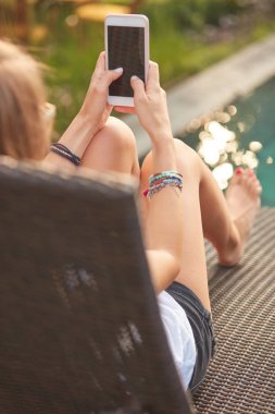 Bir yüzme havuzu güverte salonda yatarken cep telefonu kullanarak kız 