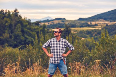 Çayırda kemerinde bıçakla poz veren yürüyüşçü.