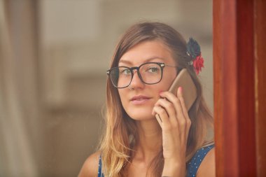 Evde akıllı telefon kullanan genç kadın. OU 'dan pencere yansıması