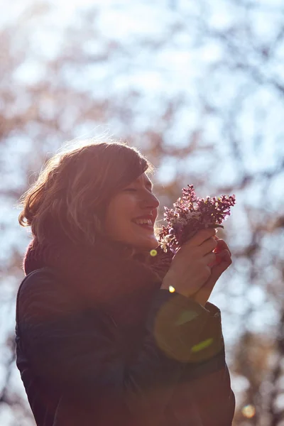 Csinos fiatal lány illatú szép csokor virágot a természetben. — Stock Fotó