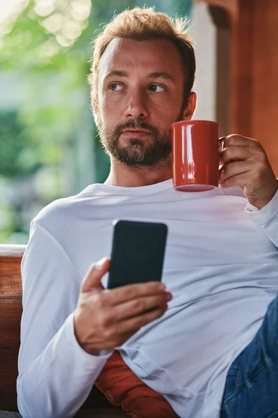 Člověk, který sedí na terase a pije kávu/čaj, zatímco usin — Stock fotografie