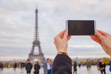 Paris geçmişi ve Eyfel kulesi olan cep telefonu kullanan bir kız.