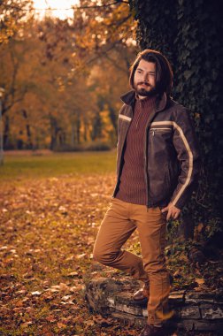 Sonbahar renkli parkta ağacın yanında poz adam.