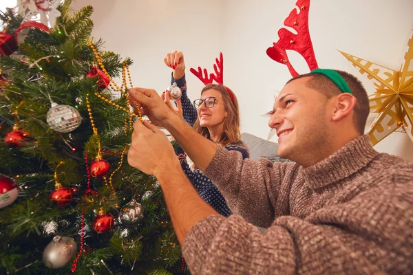 Glückliches Paar schmückt Baum für Neujahr / Heiligabend. — Stockfoto