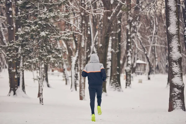 Człowiek jogging w zimnej zimie śnieżny dzień na zewnątrz. — Zdjęcie stockowe