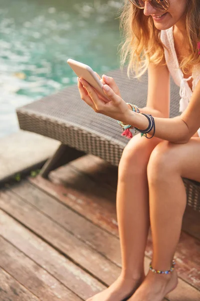 Meisje met behulp van mobiele telefoon liggend op een zwembad dek Lounge — Stockfoto