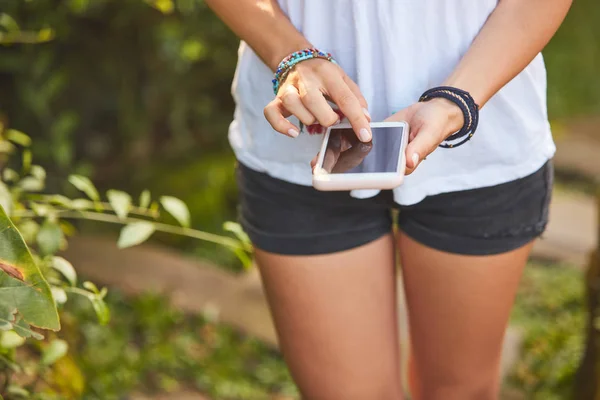 Nő használ mobilját a szabadban a parkban/kertben. — Stock Fotó