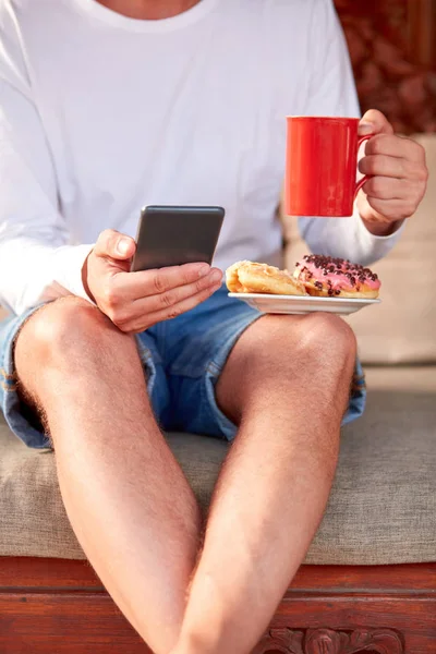 Hombre sentado en un sofá terraza y beber café / té, comer hacer — Foto de Stock
