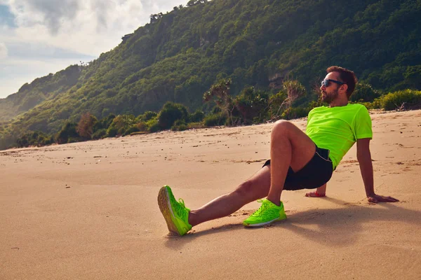 Sportivo che si estende su una spiaggia tropicale esotica dopo il jogging / — Foto Stock