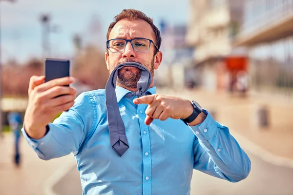 Divertido hombre de negocios enojarse mientras usa el teléfono inteligente al aire libre . —  Fotos de Stock