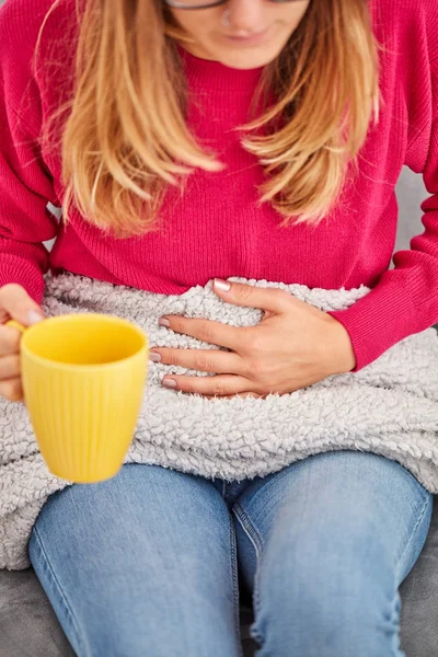 Ziek meisje Holding Cup en het drinken van koffie/thee op een bank. — Stockfoto