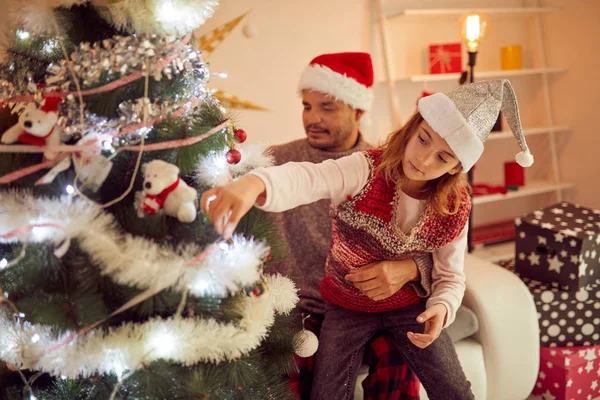 Vater und Tochter schmücken gemeinsam Weihnachtsbaum zu Hause. — Stockfoto