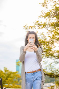 Kentsel ortamda cep telefonu kullanarak sevimli genç kadın.