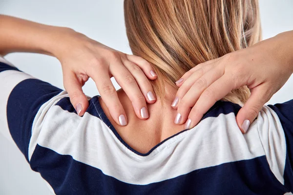 Young woman with upper back pain holding spine.