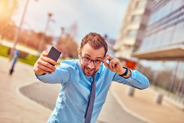 Divertido hombre de negocios con pulgares hacia arriba mientras usa el teléfono inteligente al aire libre —  Fotos de Stock