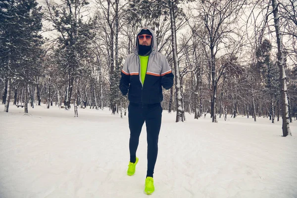Чоловік бігає в засніженому парку і холодної погоди . — стокове фото