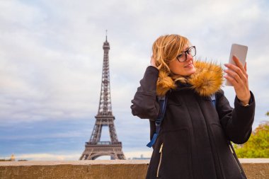 Paris geçmişi ve Eyfel kulesi olan cep telefonu kullanan bir kız.