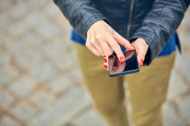 Sokakta modern akıllı telefon kullanan bir kadın..