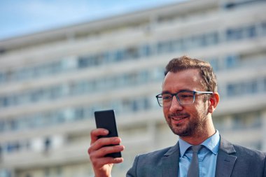 İş adamı sokakta onun Smartphone kullanarak.