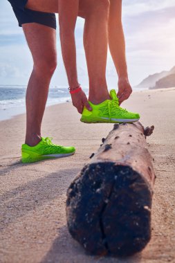 Bir tropikal egzotik plajda çalışan Sneakers bağlama adam.