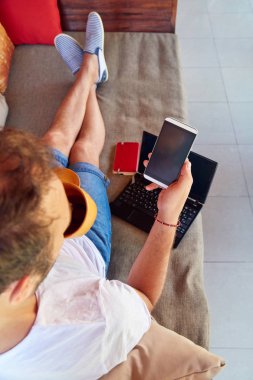 Adam cep telefonu ve laptop kullanarak TH kahve/çay içme