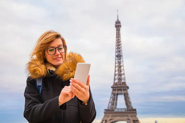 Mädchen benutzt Handy mit Pariser Hintergrund und Eiffelturm — Stockfoto