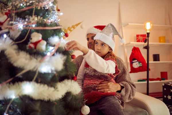 Vater und Tochter schmücken gemeinsam Weihnachtsbaum zu Hause. — Stockfoto