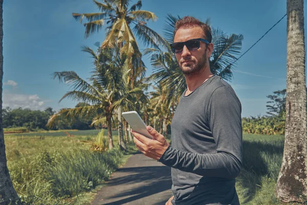Man met mobiele telefoon / smartphone in tropische omgeving. — Stockfoto
