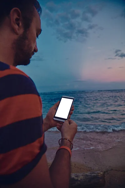 Hombre usando el teléfono celular en una playa de arena del océano . —  Fotos de Stock
