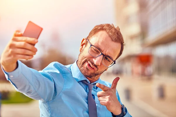 Divertido hombre de negocios con pulgares hacia arriba mientras usa el teléfono inteligente al aire libre —  Fotos de Stock