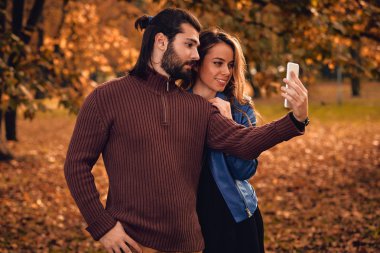 Genç çift sonbahar renkli park'cep telefonu kullanma.