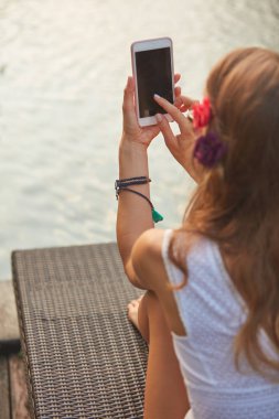 Bir yüzme havuzu güverte salonda yatarken cep telefonu kullanarak kız 