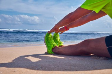 Sportsman stretching on a exotic tropical beach after jogging / 