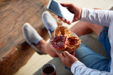 Teraskanepede oturan ve kahve/çay içen, yemek yiyen adam