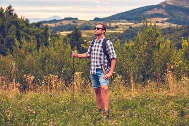 Çayırda kemerinde bıçakla poz veren yürüyüşçü.