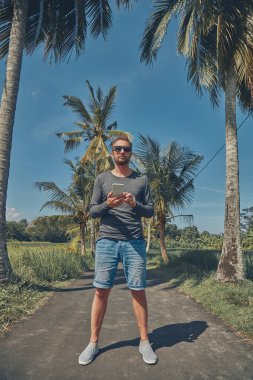 Cep telefonu kullanan adam / smartphone tropikal ortamda.