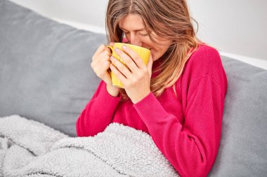 Hasta kız bir kanepede fincan ve içme kahve/çay tutarak.