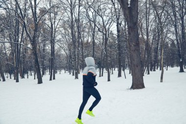 Adam karlı park ve soğuk hava koşu.